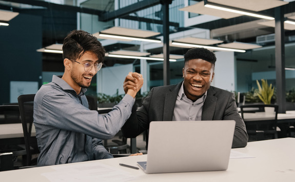 Two friends laughing at a laptop